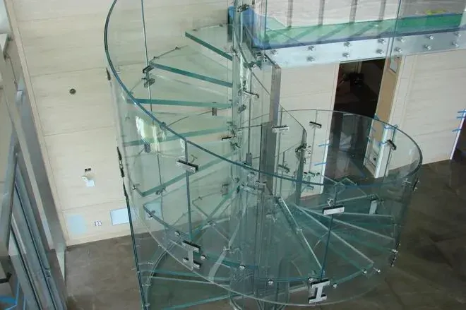 Escalera de caracol con peldaños y barandilla de vidrio curvado