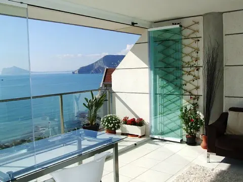 Terraza acristalada con cortina de vidrio plegable y vistas al mar